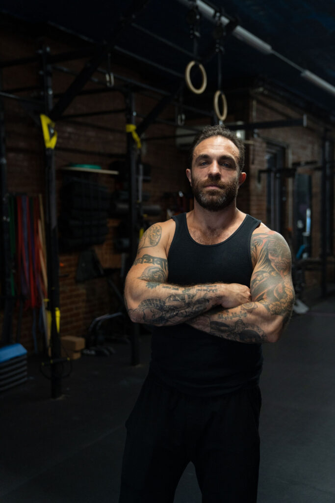 Dave Cash standing with his arms crossed under the gym rings