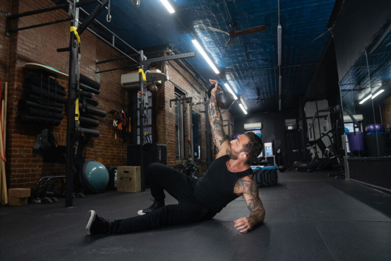 Dave Cash mid kettlebell get-up on the gym floor