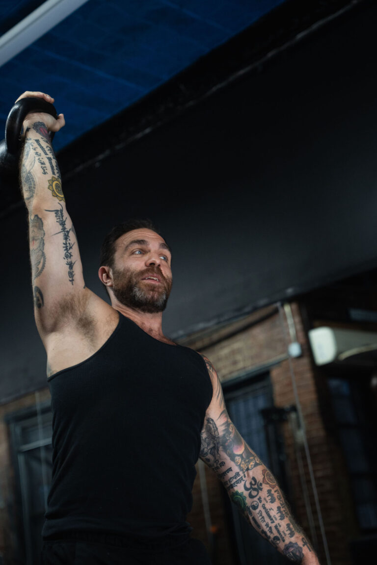 Dave Cash reaching a kettlebell overhead with a steady gaze