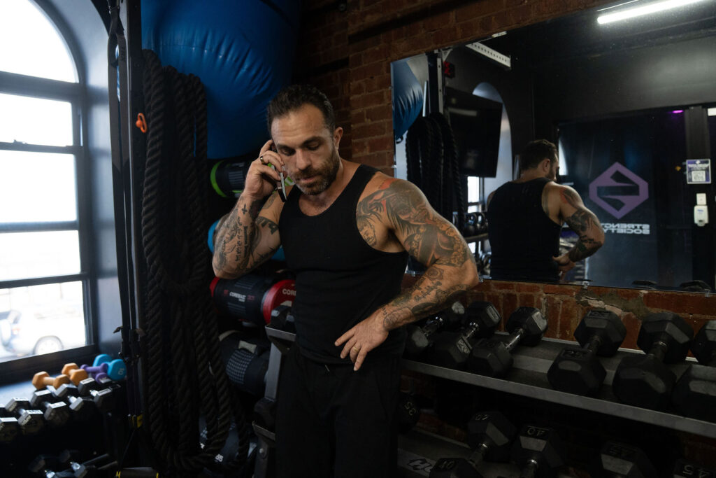 A busy man taking a phone call between sets in the gym