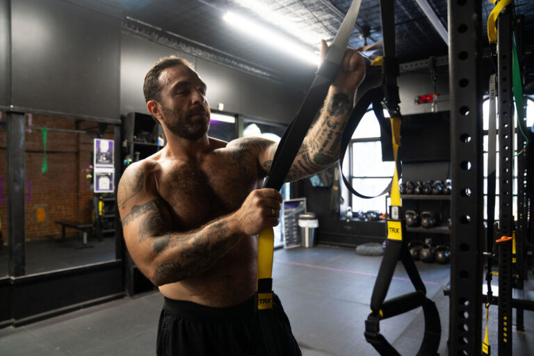 Dave Cash gripping a suspension trainer strap in the gym