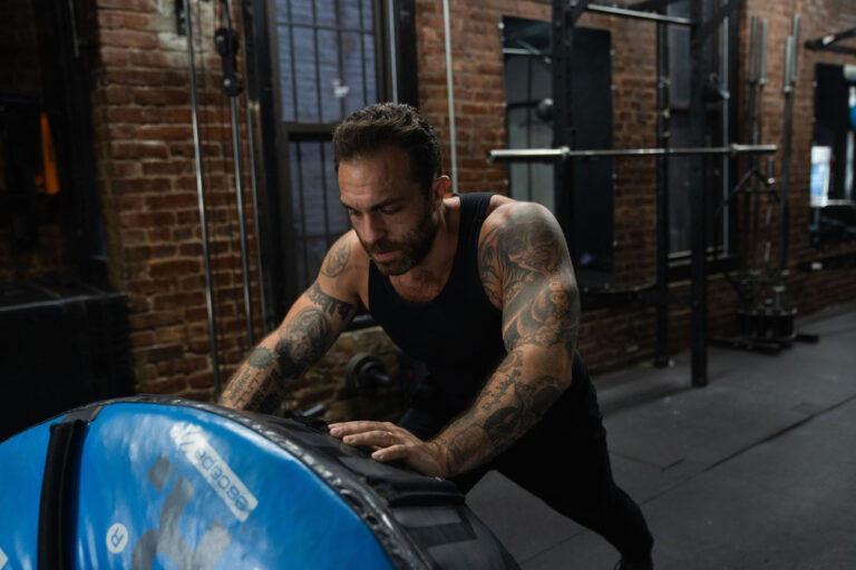 Dave Cash pushing a heavy training tire across the gym floor